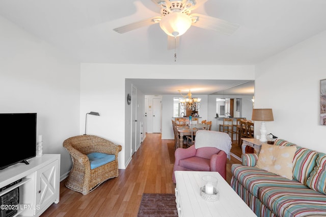 living room featuring light wood-style floors, a chandelier, baseboards, and a ceiling fan