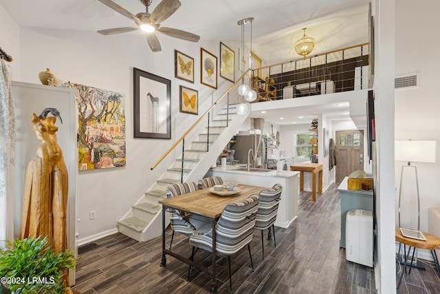 dining area with wood finish floors, visible vents, stairway, baseboards, and a towering ceiling