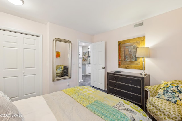 bedroom with wood finished floors, visible vents, and a closet