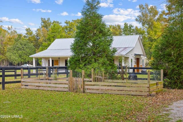 country-style home with a front yard, a fenced front yard, and metal roof