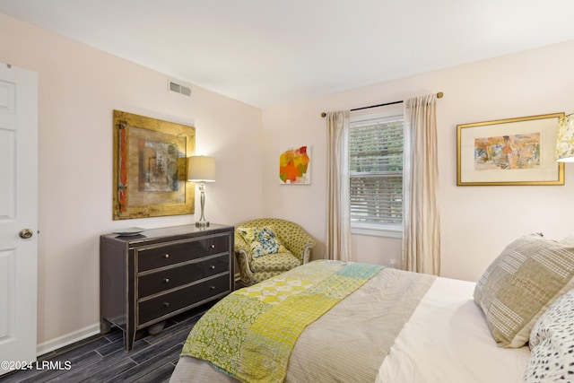 bedroom with baseboards, visible vents, and wood finish floors