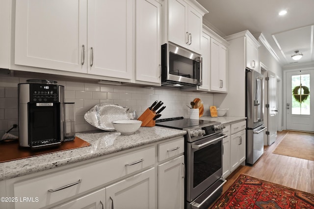 17 Marlowe Way Unit 1, Bluffton, SC 29910 - kitchen featuring stainless steel appliances, white cabinets, light wood finished floors, backsplash, and light stone countertops