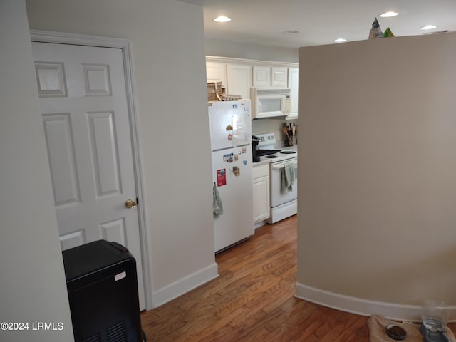 kitchen with hardwood / wood-style floors, white appliances, and white cabinets