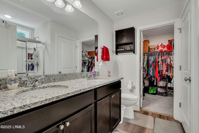 bathroom with vanity, hardwood / wood-style floors, toilet, and an enclosed shower