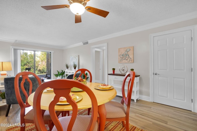 dining area featuring ceiling fan, ornamental molding, light hardwood / wood-style floors, and a textured ceiling