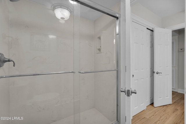 bathroom with hardwood / wood-style flooring and a shower with door