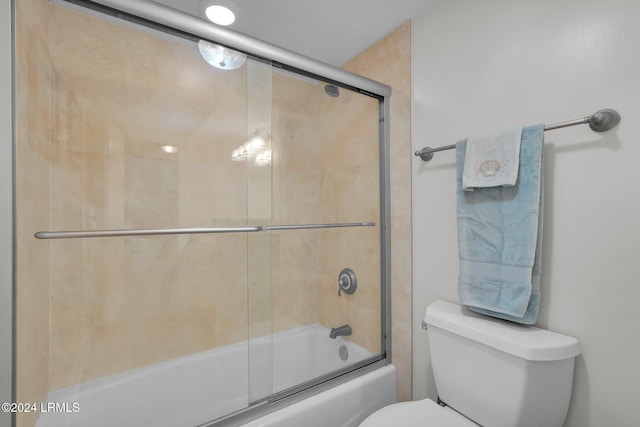 bathroom featuring bath / shower combo with glass door and toilet