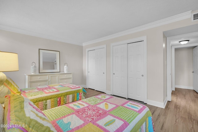 bedroom featuring multiple closets, ornamental molding, and light hardwood / wood-style floors