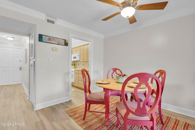 dining room with a textured ceiling, ornamental molding, ceiling fan, and light wood-type flooring