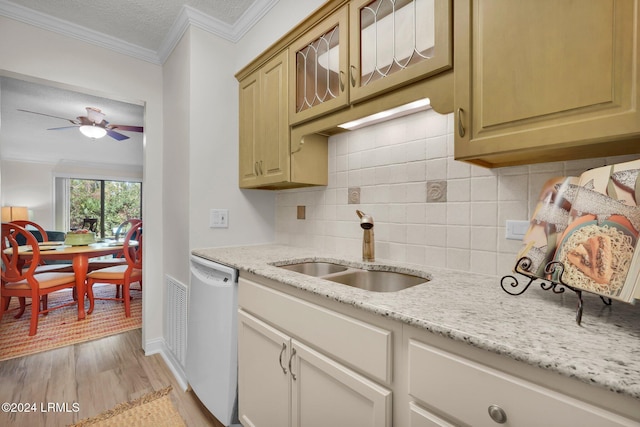 kitchen with dishwasher, sink, backsplash, light hardwood / wood-style floors, and light stone countertops