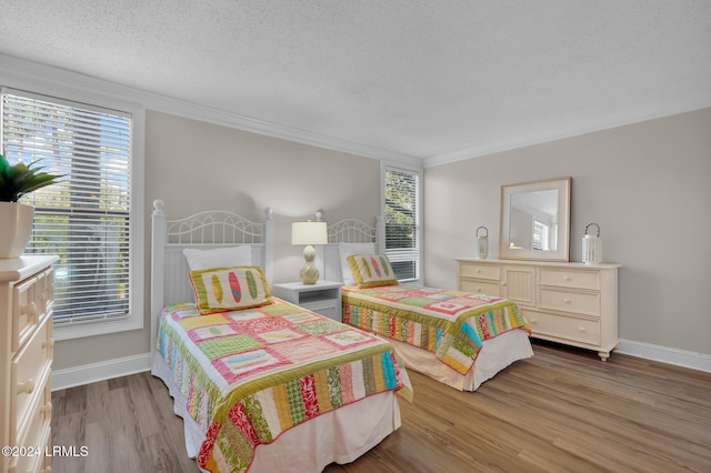 bedroom with hardwood / wood-style flooring, ornamental molding, and a textured ceiling