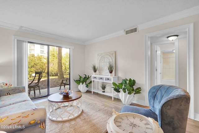 living room with light hardwood / wood-style flooring, ornamental molding, and a textured ceiling