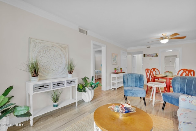 living room with crown molding, ceiling fan, and light hardwood / wood-style flooring