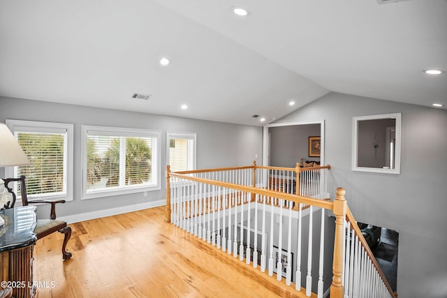 corridor with lofted ceiling, wood finished floors, an upstairs landing, and recessed lighting