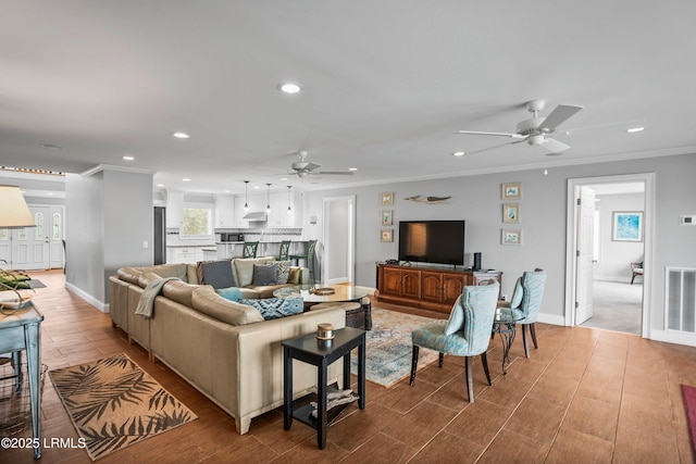 living room with ornamental molding, recessed lighting, light wood-style floors, and baseboards