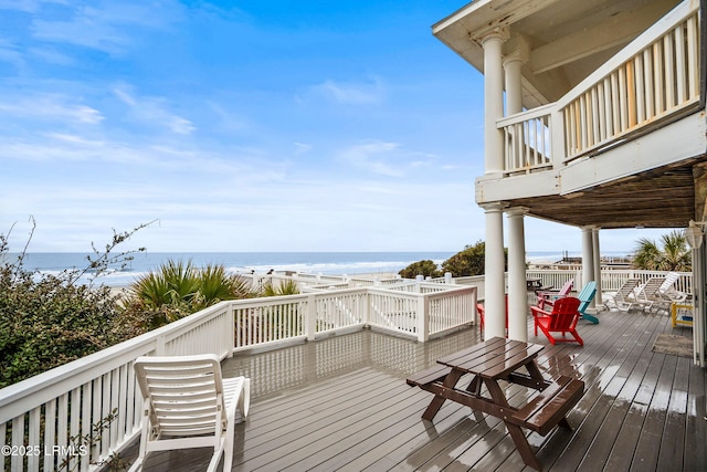 wooden deck with a water view and a beach view