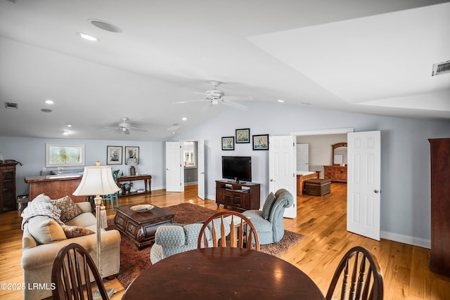 living area featuring lofted ceiling, visible vents, a ceiling fan, wood finished floors, and baseboards