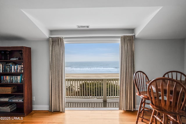 sitting room with a water view, light wood-style floors, baseboards, and a beach view