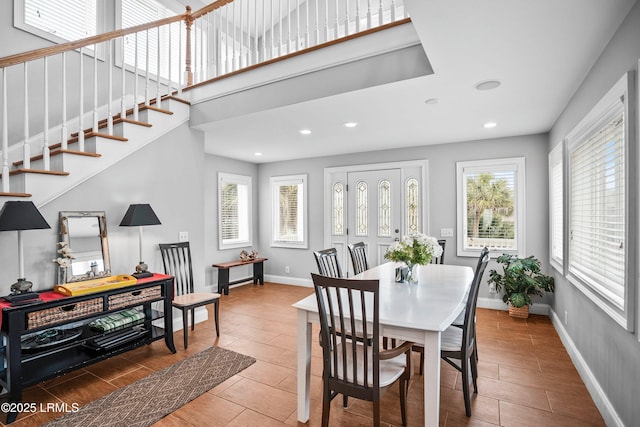 dining room featuring stairway, recessed lighting, a towering ceiling, and baseboards