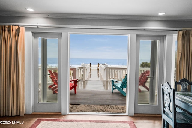 doorway to outside featuring ornamental molding, recessed lighting, a water view, and a beach view