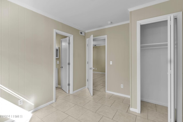 unfurnished bedroom with crown molding, a closet, and light tile patterned floors