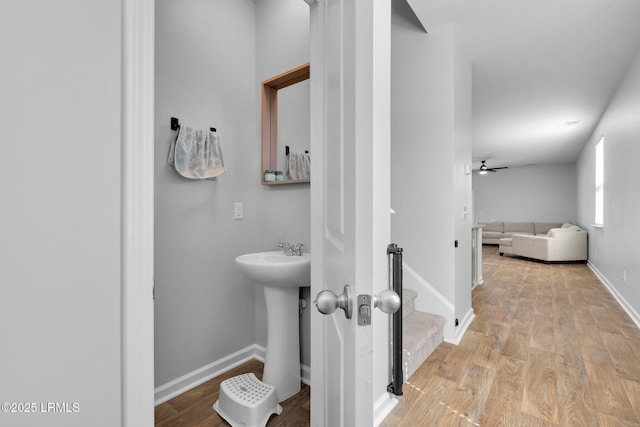 bathroom with a ceiling fan, wood finished floors, and baseboards