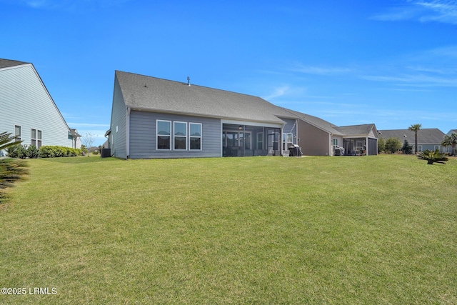 back of property with a yard, a shingled roof, and a sunroom