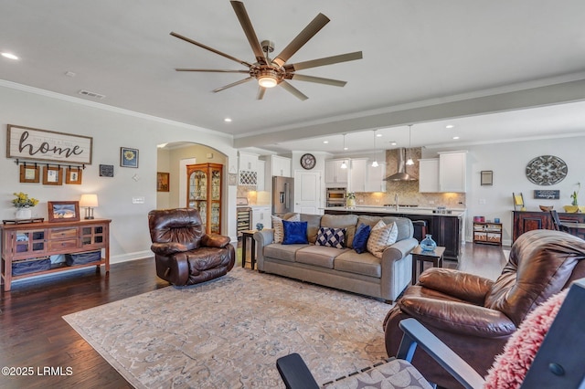 living area featuring wood finished floors, recessed lighting, arched walkways, baseboards, and ceiling fan