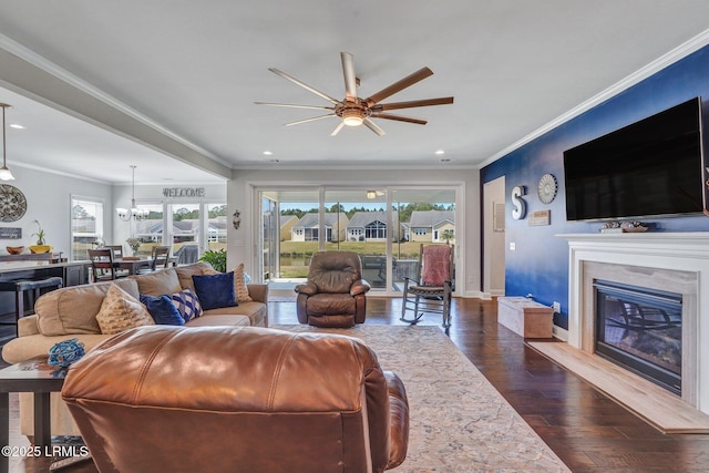 living room featuring dark wood-type flooring, a healthy amount of sunlight, a ceiling fan, and crown molding