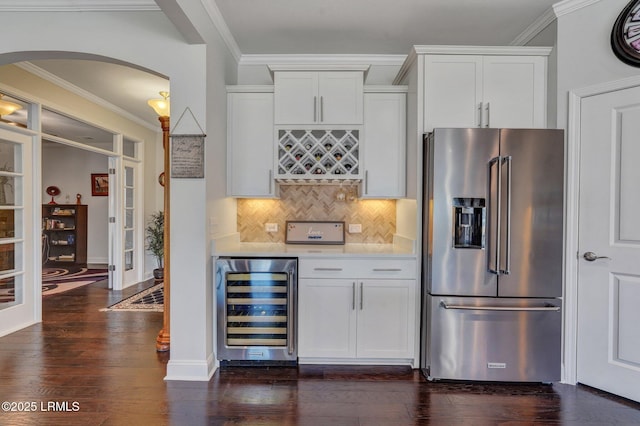 kitchen with beverage cooler, high end fridge, arched walkways, light countertops, and dark wood-type flooring