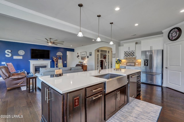 kitchen with ceiling fan, light countertops, arched walkways, stainless steel appliances, and a sink