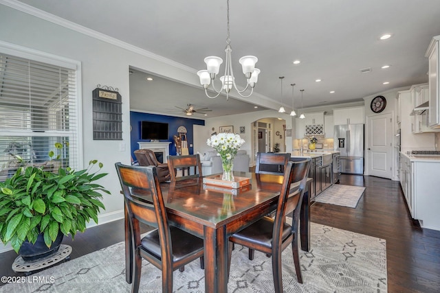 dining space with crown molding, dark wood-style floors, ceiling fan with notable chandelier, recessed lighting, and arched walkways