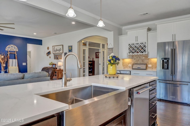 kitchen with visible vents, arched walkways, high end fridge, a sink, and open floor plan