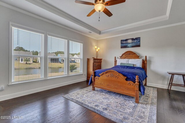 bedroom featuring hardwood / wood-style floors, a tray ceiling, crown molding, and baseboards