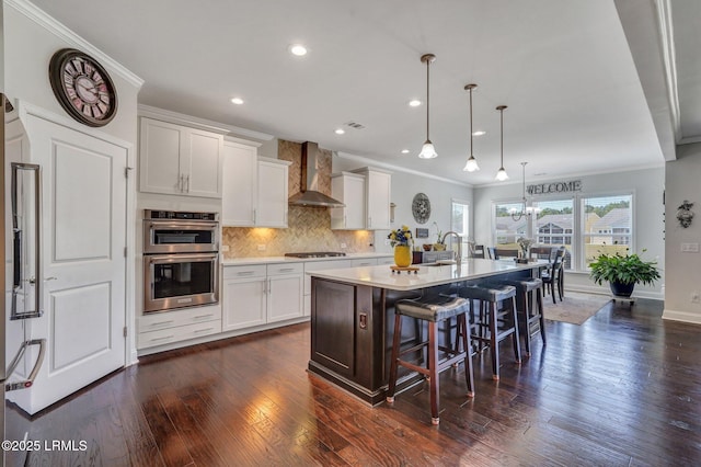 kitchen with gas cooktop, ornamental molding, decorative backsplash, double oven, and wall chimney range hood