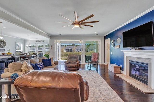 living room featuring crown molding, a premium fireplace, baseboards, ceiling fan, and dark wood-style flooring