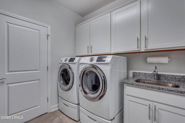 laundry area with cabinet space, independent washer and dryer, and a sink