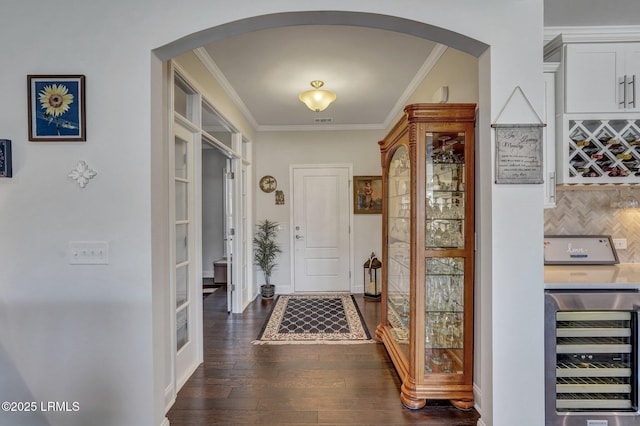 foyer entrance featuring wine cooler, arched walkways, and ornamental molding