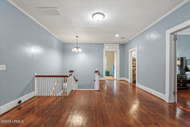 spare room featuring ornamental molding, dark wood-type flooring, a notable chandelier, and a textured ceiling