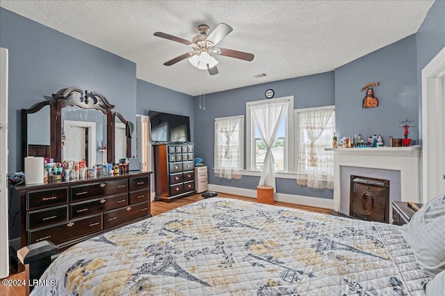 bedroom with a textured ceiling, ceiling fan, and hardwood / wood-style flooring