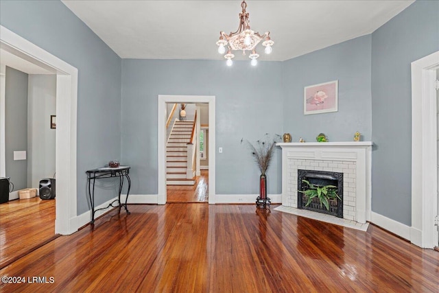 living room with hardwood / wood-style floors, a notable chandelier, and a fireplace