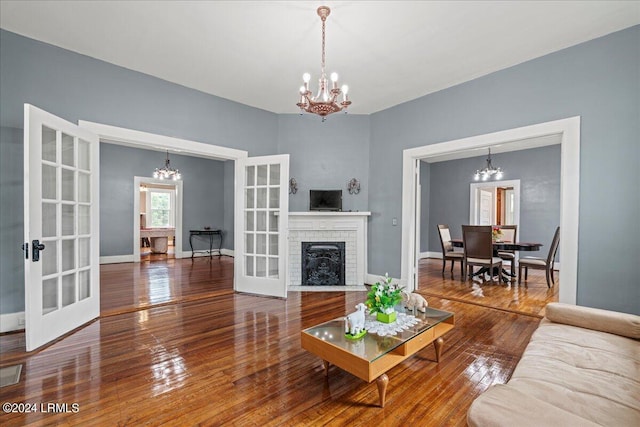 living room with a brick fireplace, a chandelier, and french doors