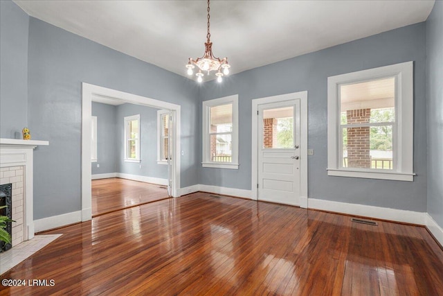 interior space with an inviting chandelier, wood-type flooring, and a brick fireplace