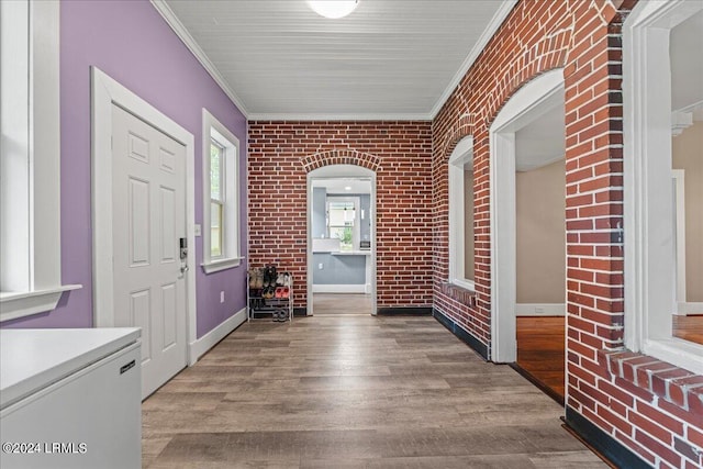 entrance foyer featuring ornamental molding, brick wall, and light hardwood / wood-style floors