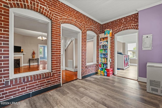 playroom featuring brick wall, hardwood / wood-style floors, a chandelier, electric panel, and crown molding