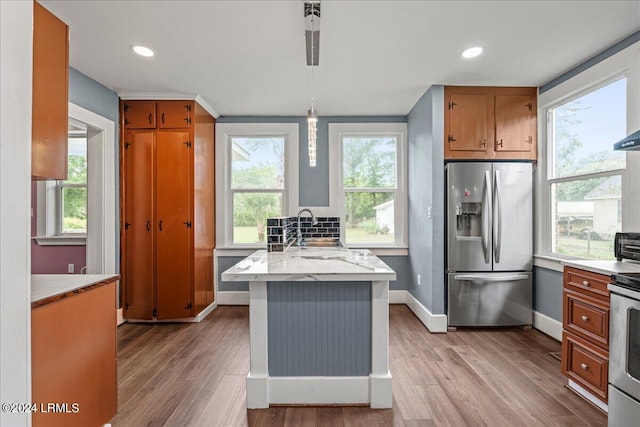 kitchen with pendant lighting, sink, light hardwood / wood-style flooring, and appliances with stainless steel finishes