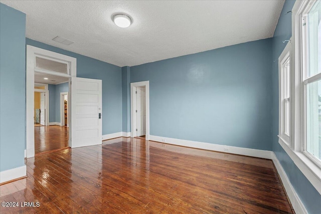 unfurnished room with hardwood / wood-style floors and a textured ceiling