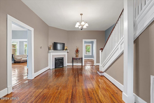 unfurnished living room featuring hardwood / wood-style flooring, a notable chandelier, and a wealth of natural light