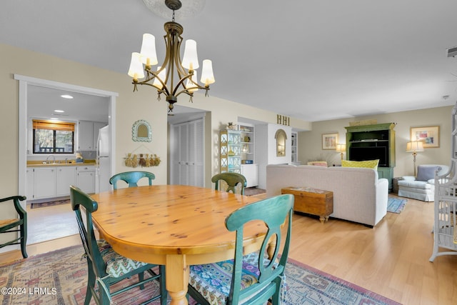 dining room featuring sink, a notable chandelier, and light hardwood / wood-style floors