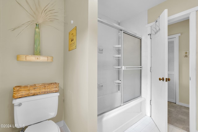 bathroom with tile patterned flooring, bath / shower combo with glass door, and toilet